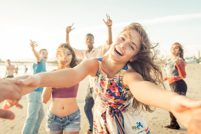 Group,Of,Friends,Having,Fun,And,Dancing,On,The,Beach.