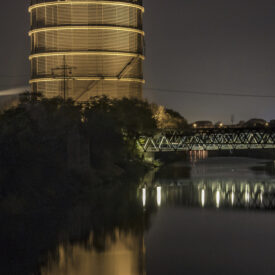 Beleuchteter Gasometer Oberhausen bei Nacht mit Spiegelung im Wasser