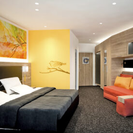 Hotelzimmer mit Betten und orangem Sitzbereich.