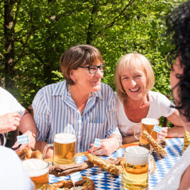 Erwachsene Gäste in geselliger Runde in einem Münchner Biergarten