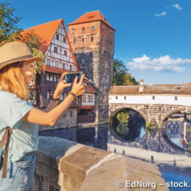 Frau fotografiert die Nürnberger Altstadt an einem Fluss