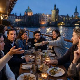 Freundesgruppe beim Abendessen auf einem Moldauschiff vor der Prager Altstadt