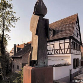 Skulptur vor historischen Fachwerkhäusern in Speyer