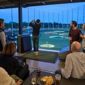 Freundesgruppe verfolgt einen Abschlag in einer Golf-Entertainment-Bay in Oberhausen