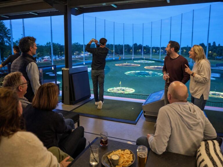 Freundesgruppe verfolgt einen Abschlag in einer Golf-Entertainment-Bay in Oberhausen