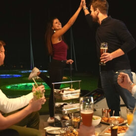 Freunde sitzen mit Getränken und Snacks beim TOPGOLF-Abend in Oberhausen zusammen
