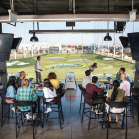 Gruppe beim TOPGOLF in Oberhausen in einer Bay mit Blick auf das Spielfeld