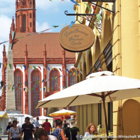 Belebte Gasse in der Würzburger Altstadt mit Kirchturm