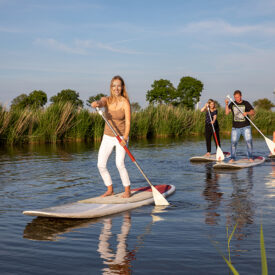 Gäste beim Stand-up-Paddling auf einem Siel in Neuharlingersiel
