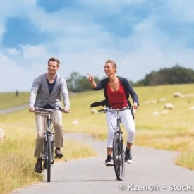 Zwei Personen fahren mit dem Fahrrad durch die Küstenlandschaft bei Neustadt