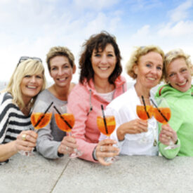 Freundinnen stoßen am Strand von Norderney mit einem Aperitif an
