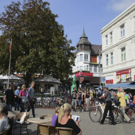 Belebte Innenstadt von Norderney mit Radfahrern und Straßencafés