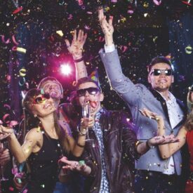 Feiernde Gäste mit Partybrillen und Konfetti bei einer Norderney-Reise