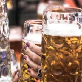 Mehrere Gäste stoßen im Festzelt beim Oktoberfest Münster mit Maßkrügen an